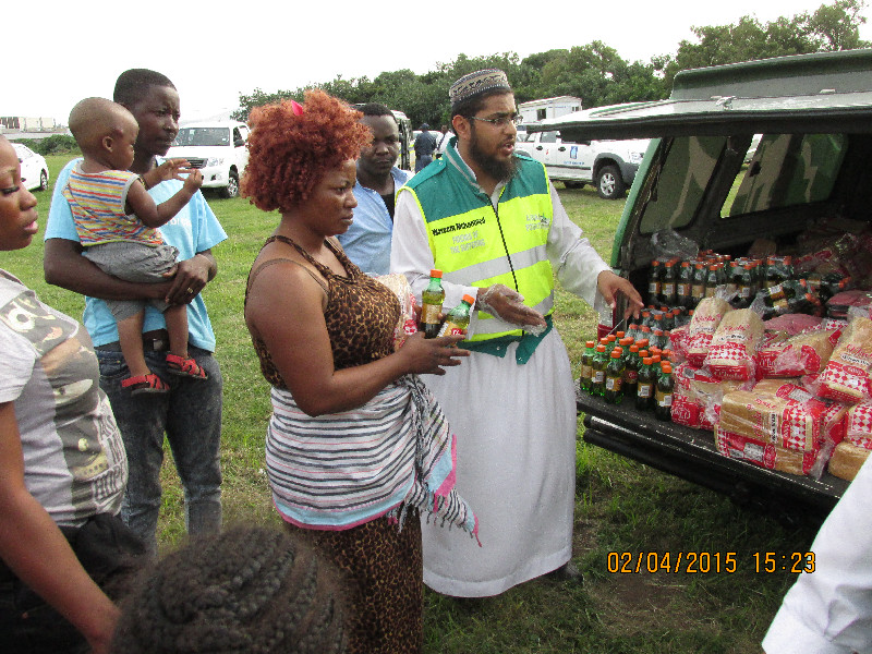 Al-Imdaad team members distribute bread and beverages to the displaced foreigners as they arrive at the camp