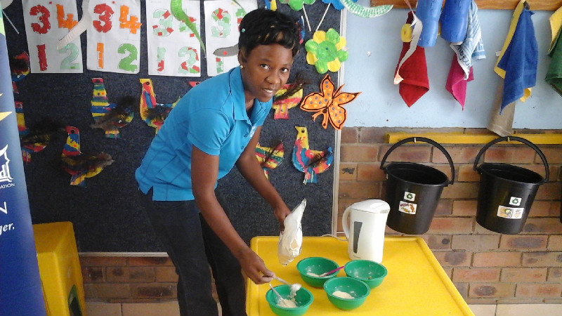 A teacher helps to prepare the cereal for the kids ahead of the school day